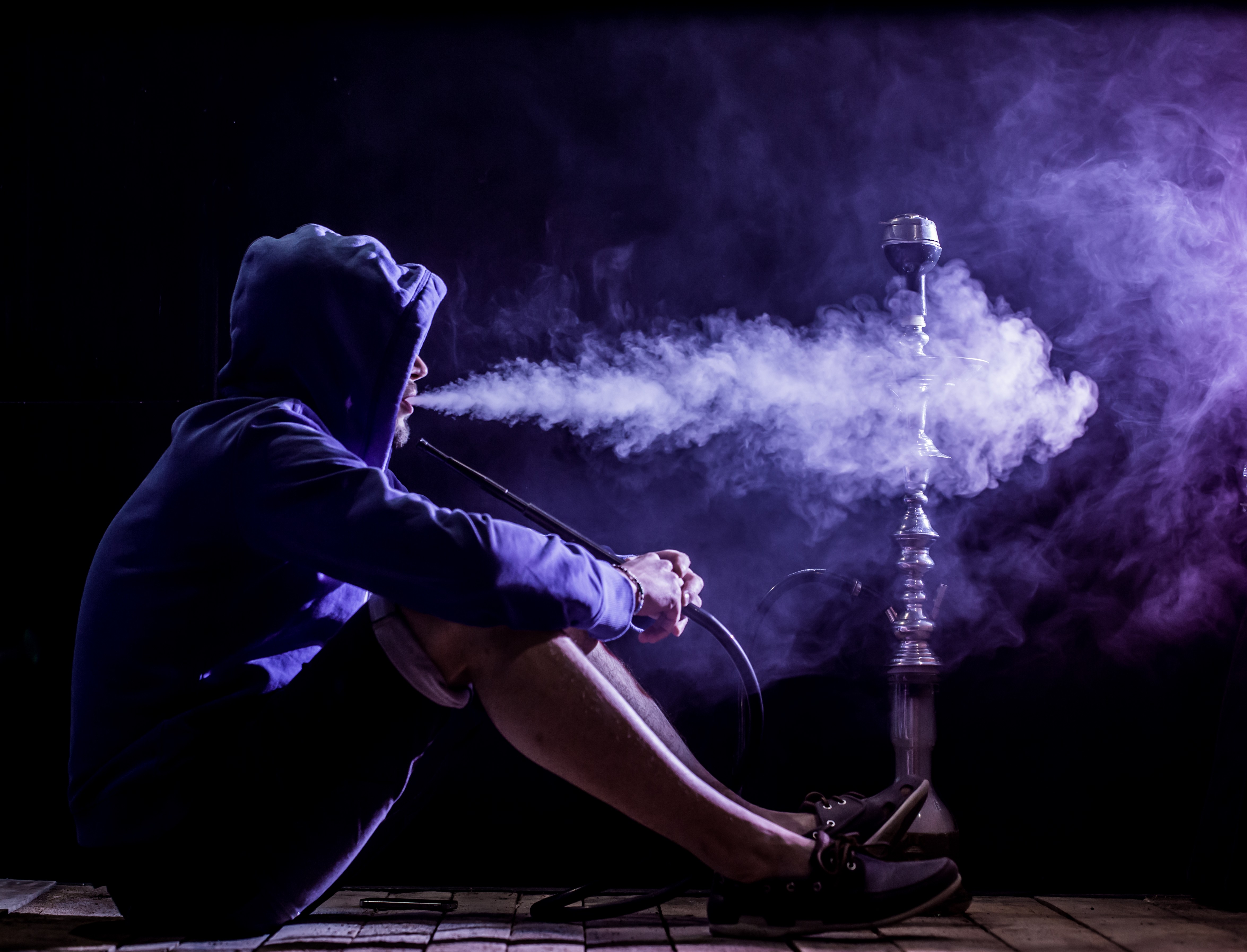 a man smokes a hookah on a black background, beautiful lighting