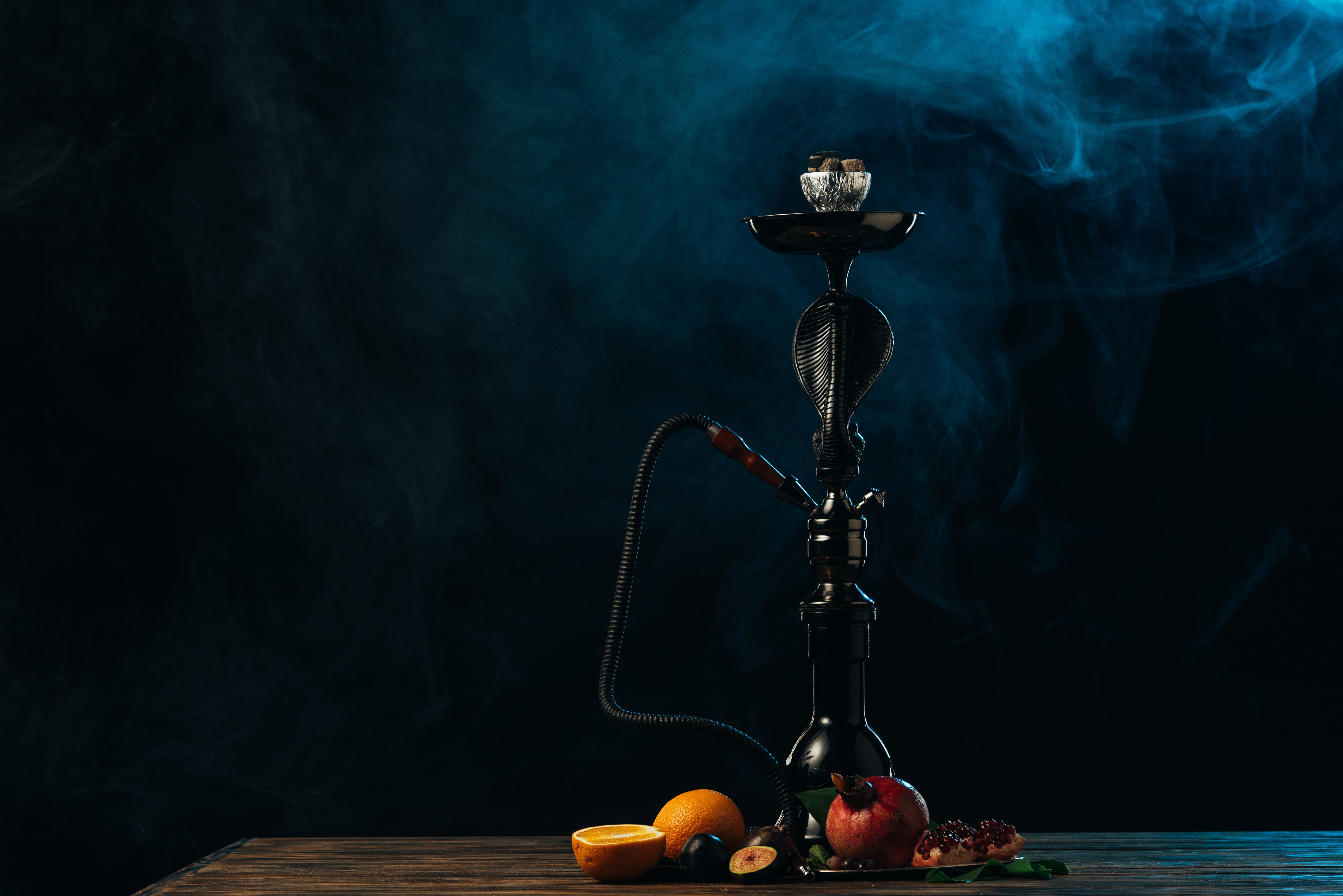 hookah with exotic fruits on wooden surface in blue smoke